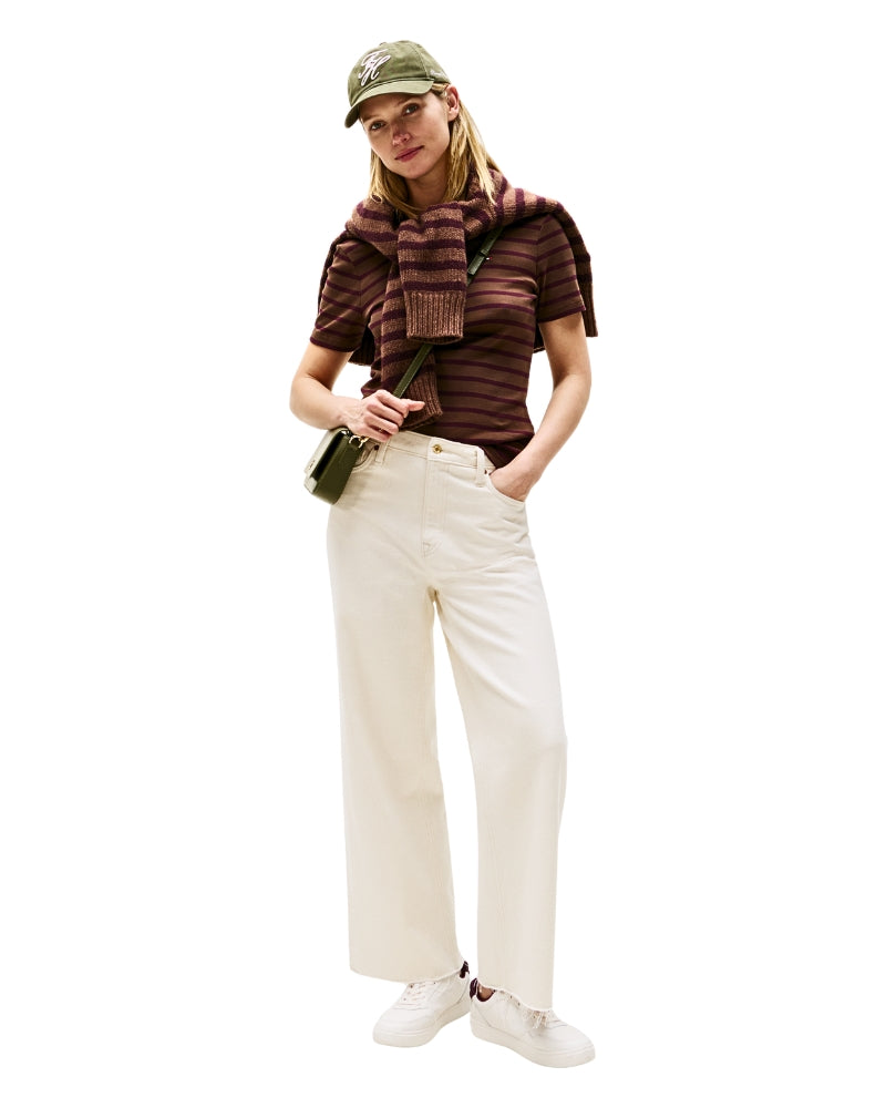 Model wearing white jeans and stripe shirt paired with Tommy Hilfiger White Trainers