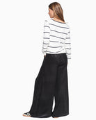 Back view showing wide-leg drape of black velvet trousers